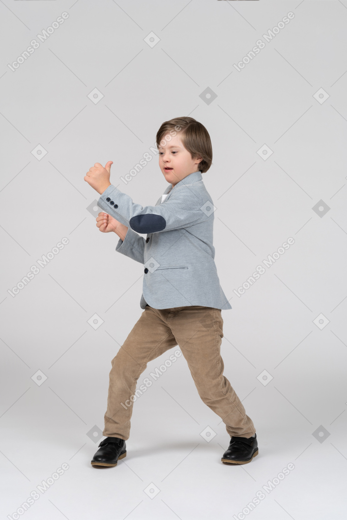Young boy in gray jacket and khaki pants dancing