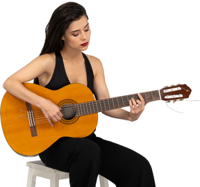 ギターを弾く黒いスーツを着て座っている若い女性の正面図