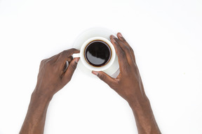 Mani maschii nere che tengono tazza di caffè nero