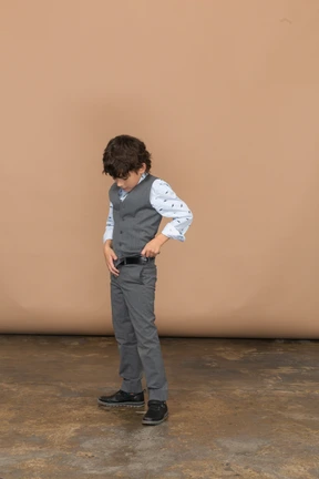 Front view of a boy in suit standing with hands on belt