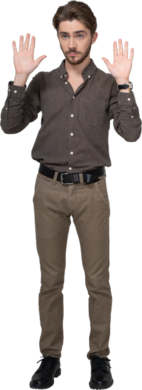 Vista frontal de um jovem com roupa de escritório, levantando as mãos