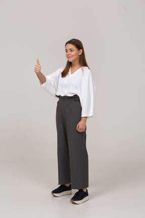 Three-quarter view of a young lady in office clothing showing thumbs up