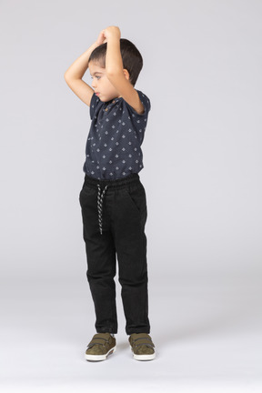 Vista frontal de um lindo menino posando com as mãos acima da cabeça
