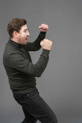 Side view of a cheerful male football fan clenching fists