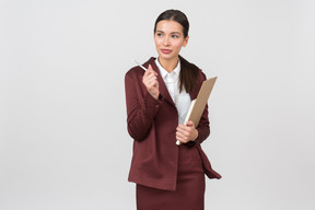 Attraente donna vestita formalmente con una lavagna per appunti che punta a qualcosa