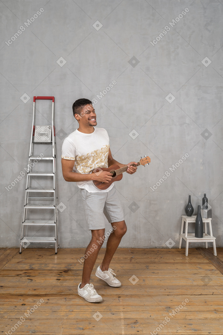 Three-quarter view of a man playing ukulele and enjoying himself