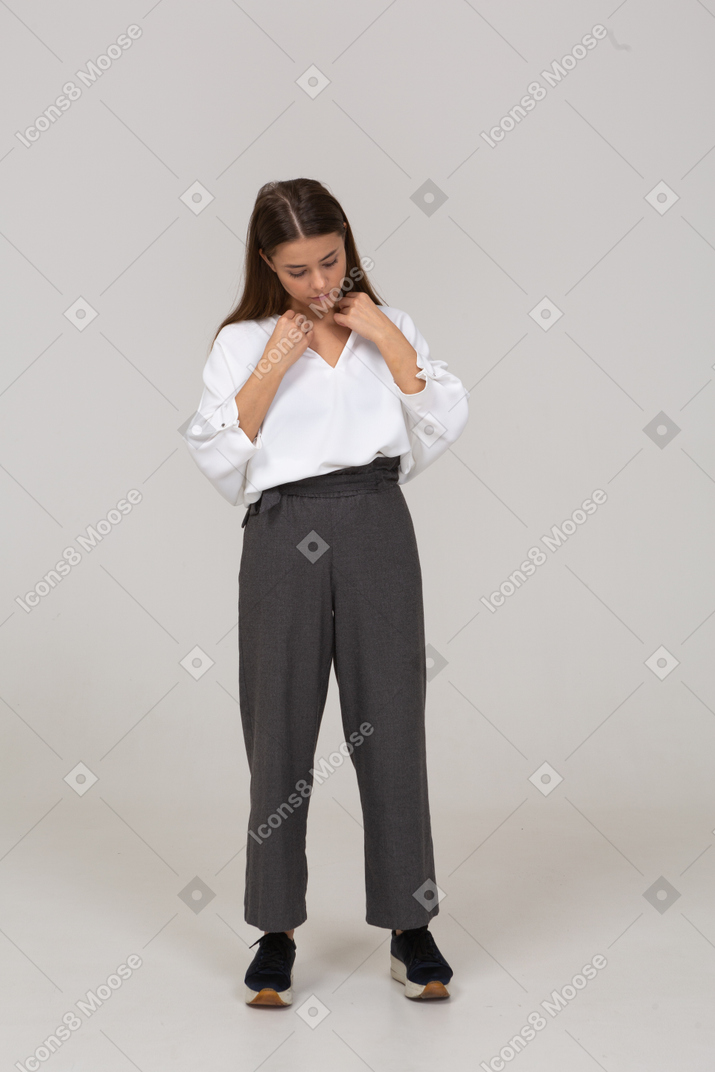 Vista frontal de una joven en ropa de oficina ajustando su blusa