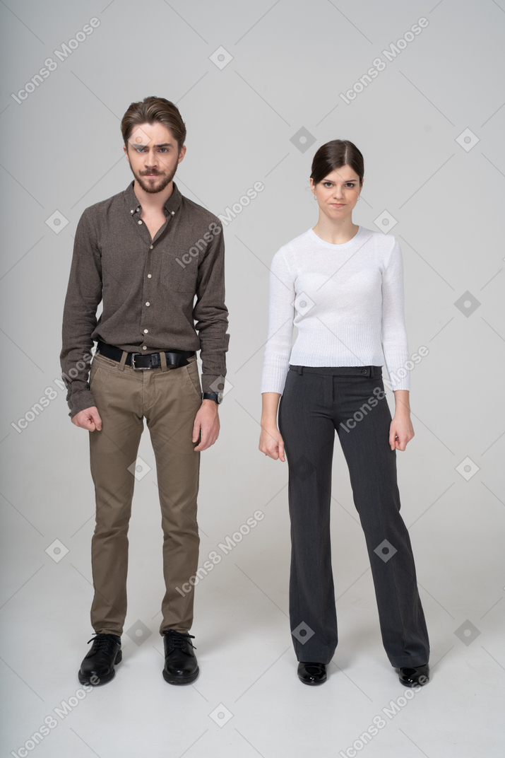 Vista frontal de um jovem casal com roupas de escritório pressionando os lábios