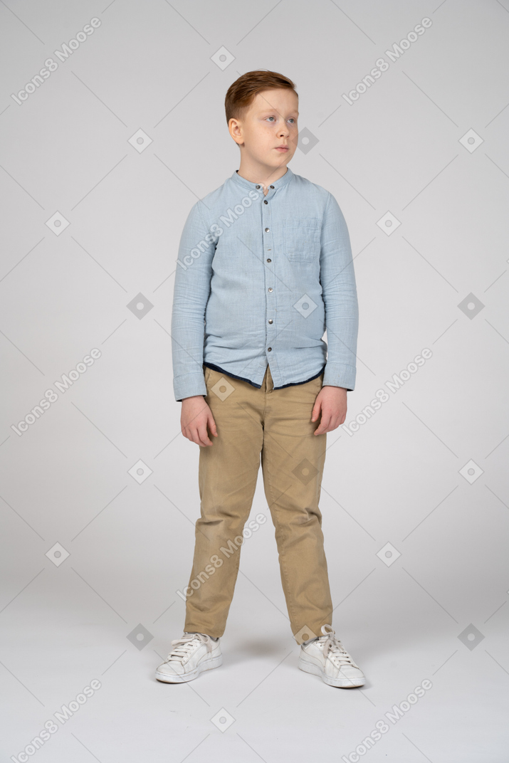 Вид спереди симпатичного мальчика в повседневной одежде, смотрящего в сторону