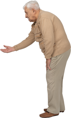 Вид сбоку на старика в повседневной одежде, стоящего с протянутой рукой
