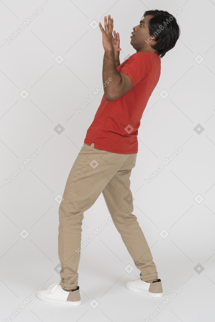 Surprised young man leaning backwards with raised hands