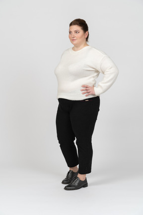 Mujer de talla grande en suéter blanco de pie con las manos en las caderas