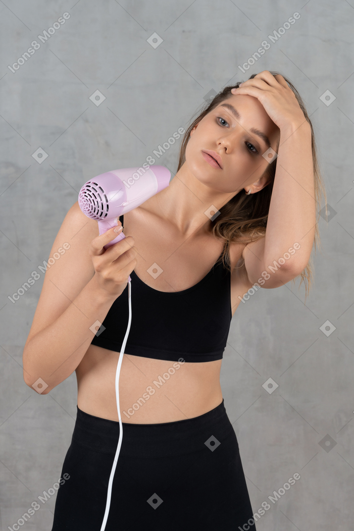 Portrait of a young woman blow-drying her hair