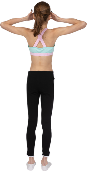 Back view of a teen girl in sportswear raising hands and hiding eyes