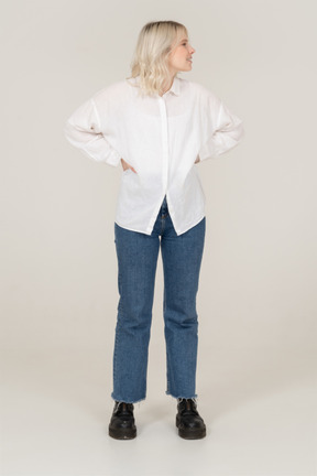 Front view of a blonde female in casual clothes putting hands on hips and looking to the right