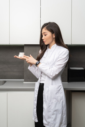 Vista frontale di una dentista femminile che tiene un prototipo di mascelle sul palmo della mano e guarda da parte