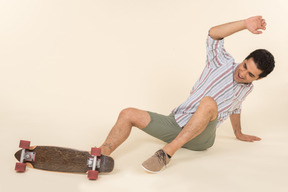 A nice-looking caucasian guy in a striped t-shirt, having fun learning how to ride a skateboard