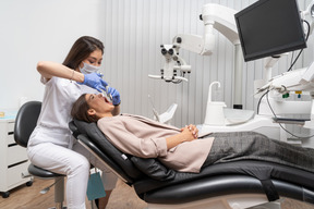 A figura intera di un dentista femminile che fa un'iniezione al suo paziente in un armadietto dell'ospedale