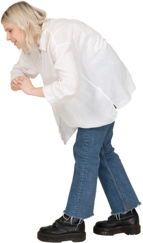 Vista lateral de una mujer rubia en ropa casual mostrando un gesto de corazón mientras se dobla