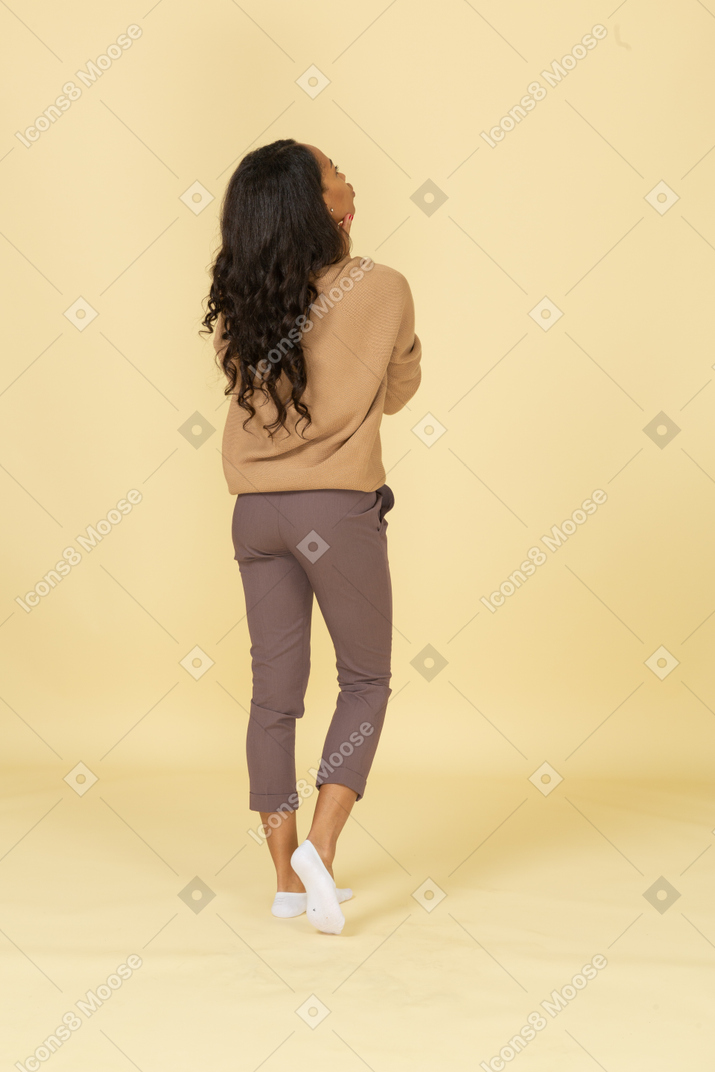 Vista posteriore di tre quarti di una giovane donna dalla carnagione scura che si tocca il collo