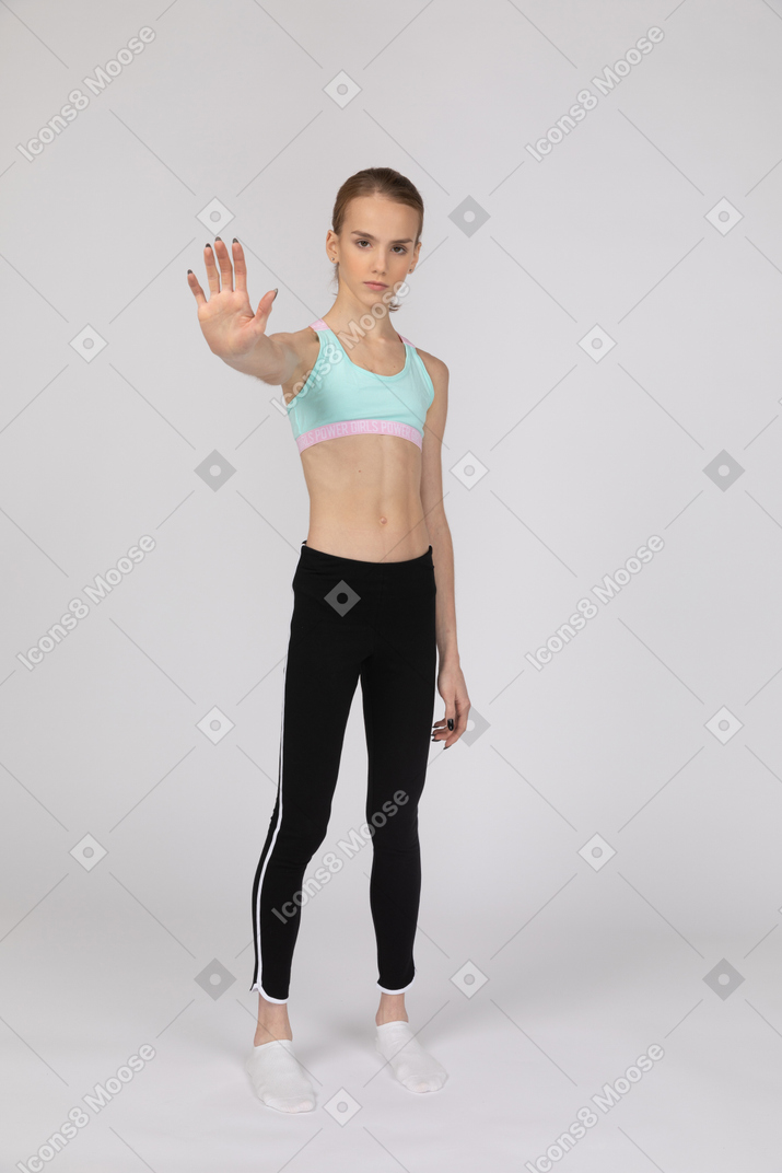 Девушка-подросток в спортивной одежде показывает жест остановки
