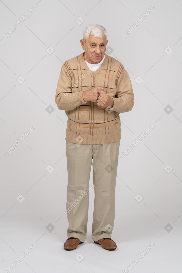 Vista frontal de un anciano con ropa informal de pie con los puños apretados y mirando a la cámara