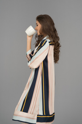Belle femme arabe debout sur le côté et boire dans une tasse blanche