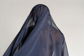 Vista frontal de un joven afro cubierto con un chal azul oscuro