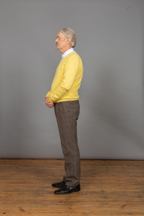 一个老人在黄色套头衫，手牵着手，闭着眼睛的侧视图
