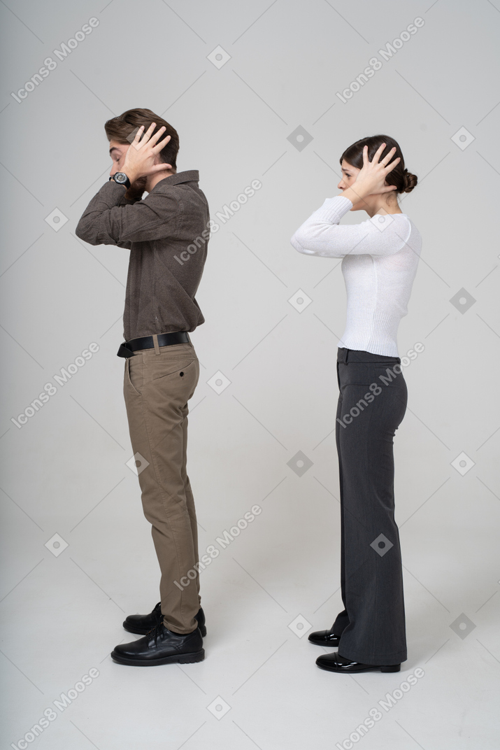 Side view of a young couple in office clothing touching head