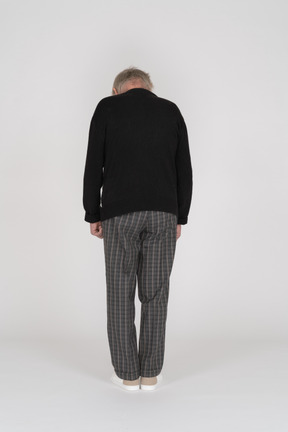 Back view of an elderly man standing and looking down