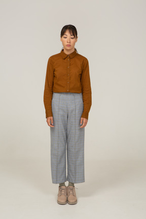 Front view of a young asian female in breeches and blouse standing still