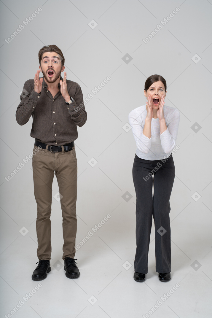 Front view of an emotional gesticulating young couple in office clothing