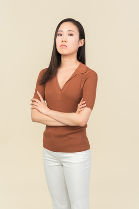 Serious looking young asian woman standing with hands crossed