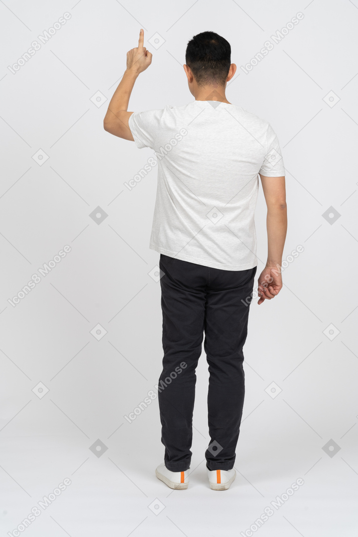 Rückansicht eines mannes in freizeitkleidung, der mit dem finger nach oben zeigt