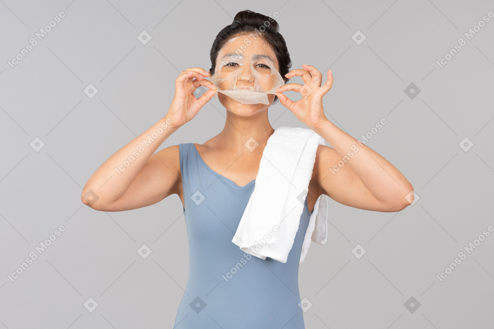 Young indian woman with white towel on shoulder peeling off face mask