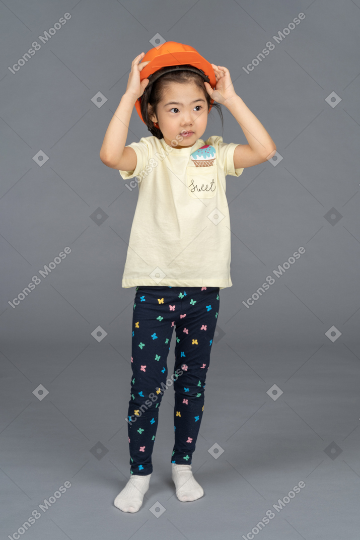Portrait of a little girl taking off a hard hat