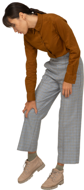 Vista frontal de uma jovem mulher asiática de calça e blusa, inclinada para a frente