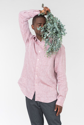 Good looking young man holding green branches