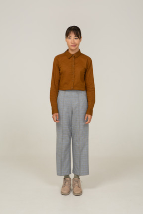 Front view of a pouting young asian female in breeches and blouse standing still