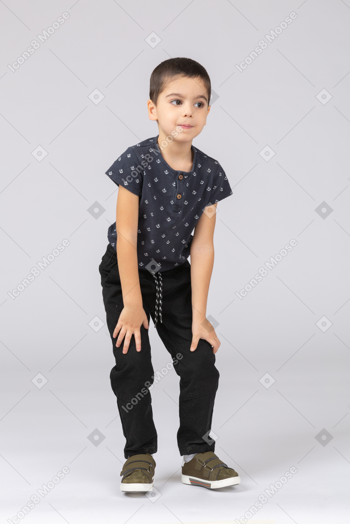 Front view of a cute boy bending down and touching knees
