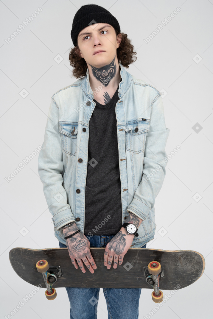 Tattooed teenager holding a skateboard
