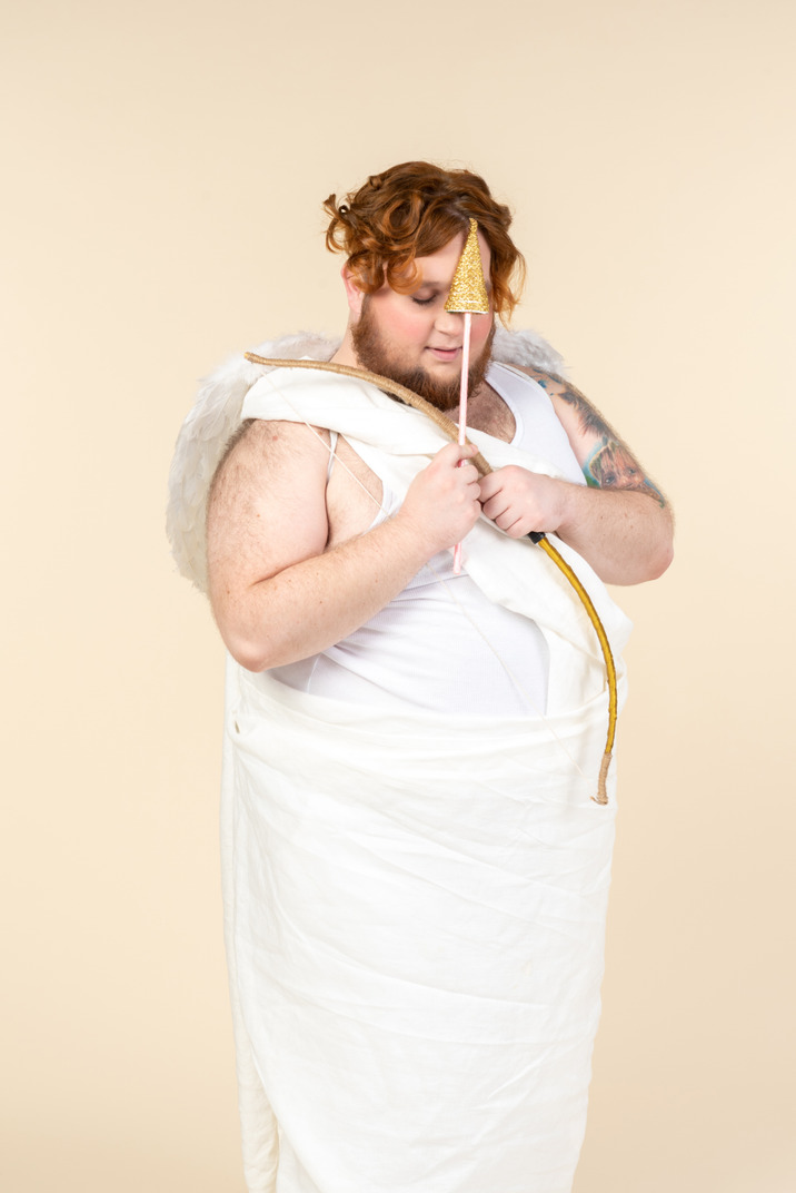 Big guy dressed as a cupid adjusting bow and arrow