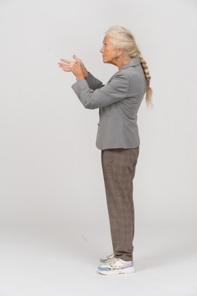 Vista lateral de una anciana en traje explicando algo