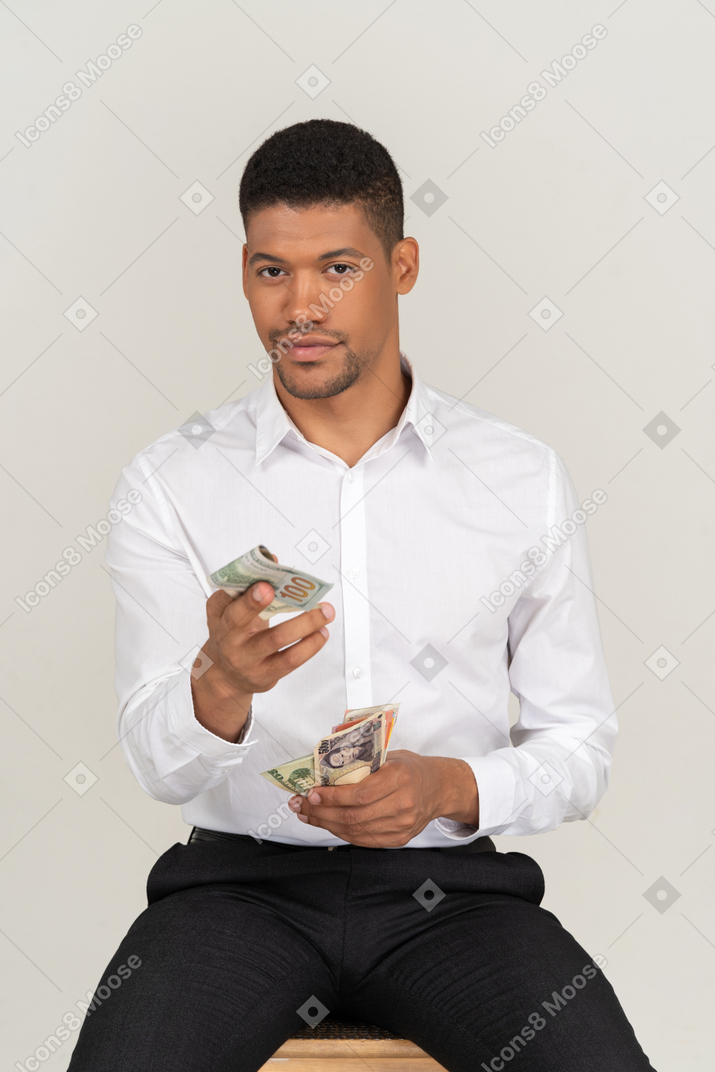 A man sitting on a stool holding money