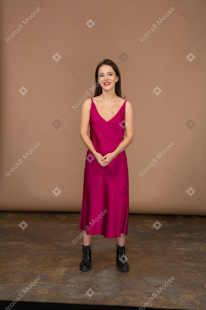 Вид спереди счастливой молодой женщины в красивом красном платье, смотрящей в камеру