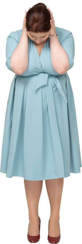 Front view of a woman in blue dress touching head