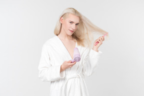 Young blond-haired man in a white bathrobe going about his morning routine