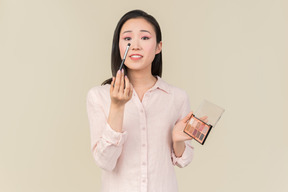 Giovane donna asiatica focalizzata sull'applicazione ombretto
