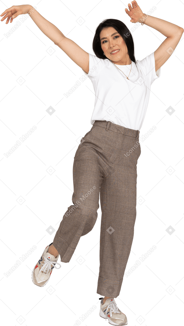 Front view of a dancing young lady in breeches and t-shirt raising hands